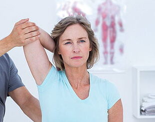 A woman is stretching her arm with another person.